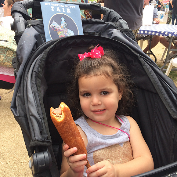 Madelyn eats her first corn dog. She gives it two paws up. 